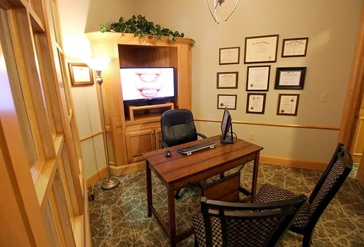 The private consultation room, with a desk and framed certificates.
